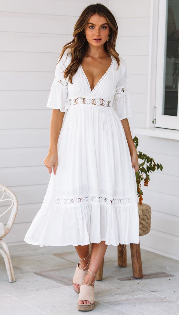 White lace dress with V-neck and ruffles at the hem 