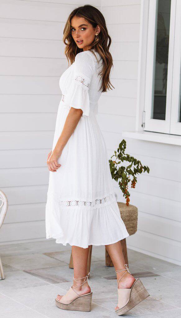 White lace dress with V-neck and ruffles at the hem 