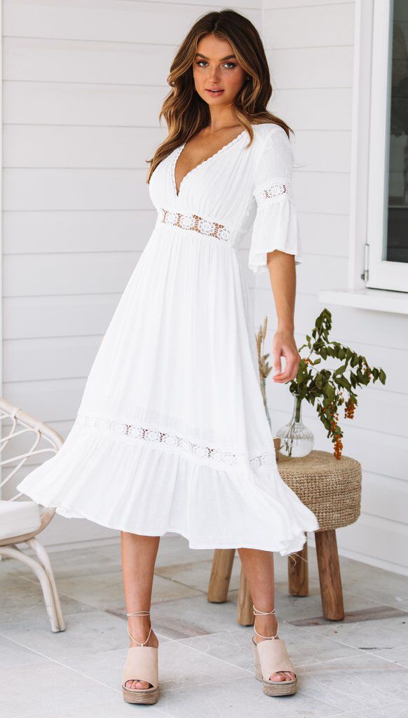 White lace dress with V-neck and ruffles at the hem 