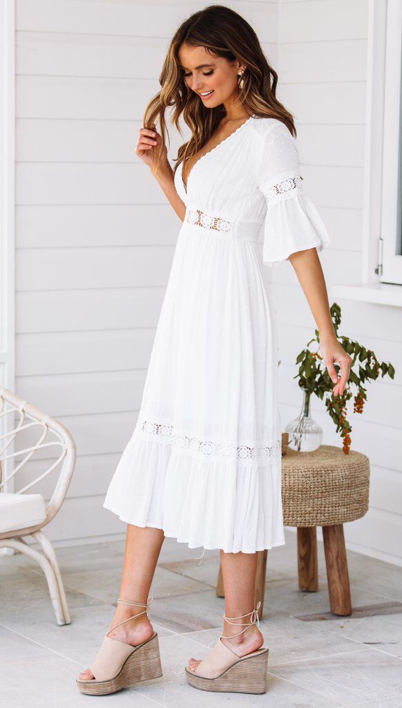 White lace dress with V-neck and ruffles at the hem 